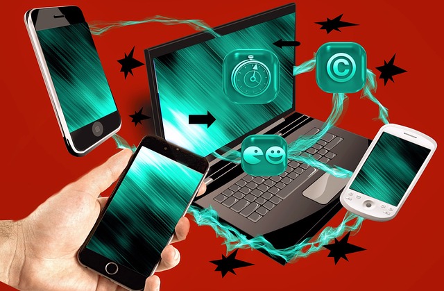 a hand holding a phone and a laptop