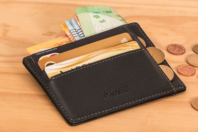 Black leather wallet on wooden table with money and credit cards – symbolizing financial literacy