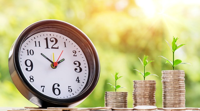 A clock and stacks of coins with small plants growing on top, symbolizing **small investment ideas** and financial growth over time.