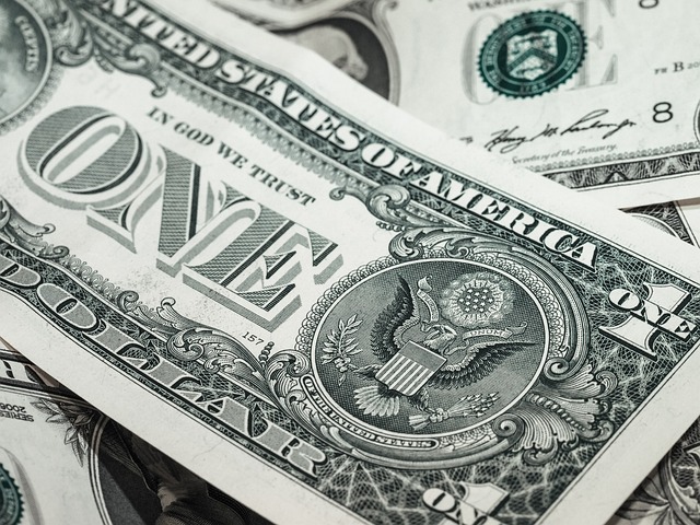Several one-dollar bills prominently displaying "ONE" and "IN GOD WE TRUST," symbolizing **Top Financial News Today USA** and economic updates.