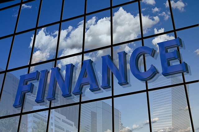 Large blue 3D letters spelling "Finance"reflected on a glass building, symbolizing Top Business Finance and corporate financial strategies.