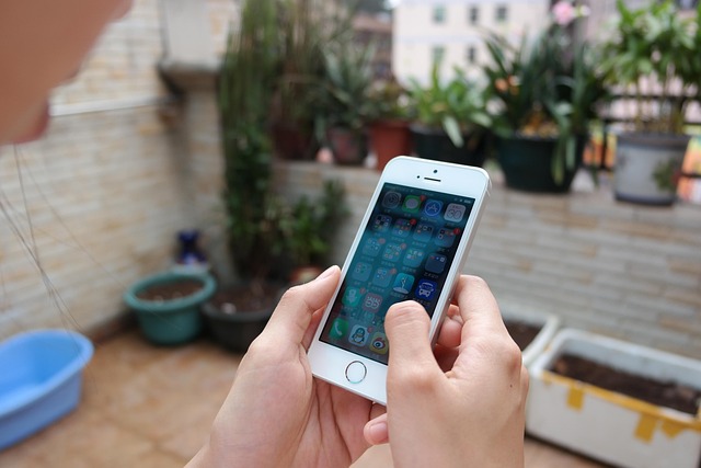 5 Areas of Personal Finance—A person holding a smartphone outdoors with various financial app icons on the screen, symbolizing the integration of digital tools in managing budgeting, saving, investing, insurance, and retirement planning.