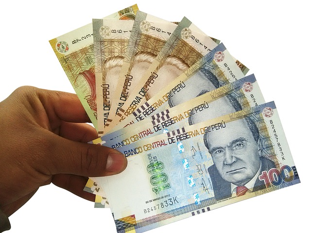 "Hand holding Peruvian banknotes of various denominations, symbolizing strategies to pay off debt fast with low income."